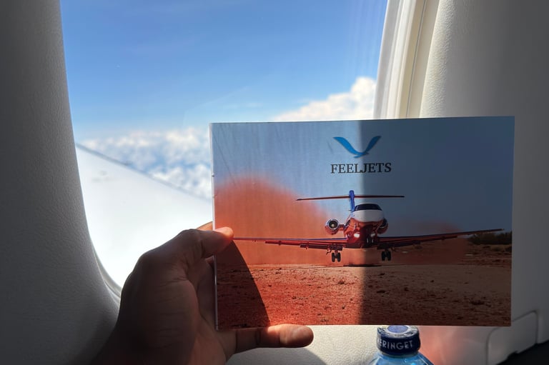Hand holding FEELJETS brochure with helicopter image near airplane window overlooking clouds