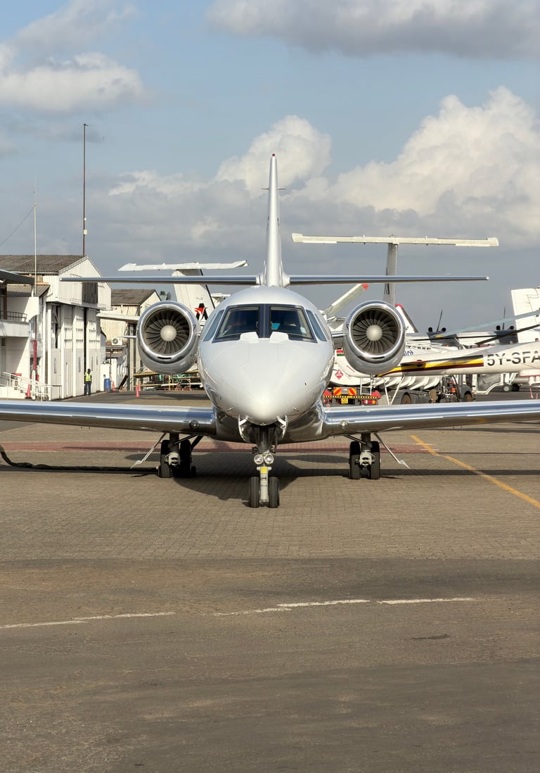 White twin-engine aircraft parked on airport tarmac with cargo and support vehicles in background