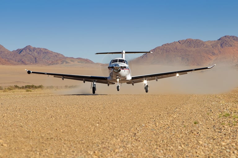 Small twin-engine airplane on desert runway with mountains in background under clear sky