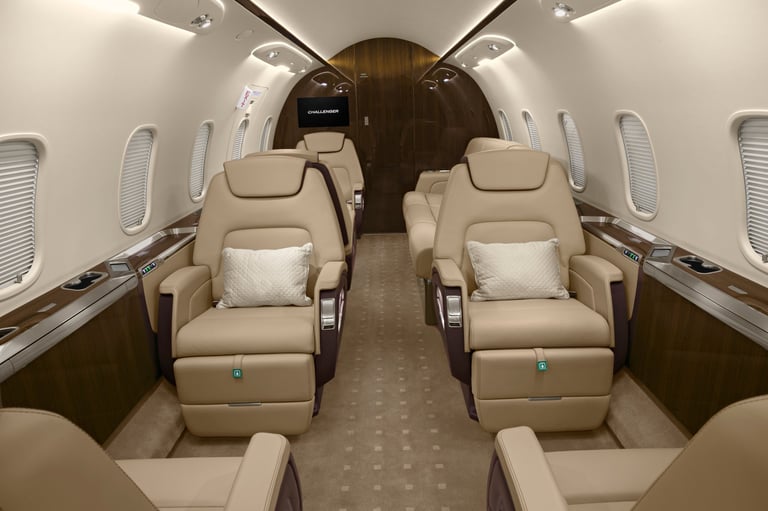 Interior of a private jet cabin with beige leather seats arranged symmetrically on both sides, wood-toned accents, and cabin windows